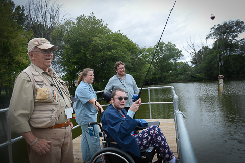 Recreation therapy patients and staff fishing off a dock with water in the background
