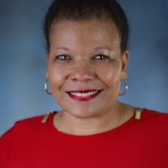 Adrin Hamilton smiles in front of a grey/blue background