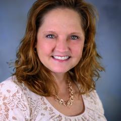 Susan smiles in front of a grey/blue background
