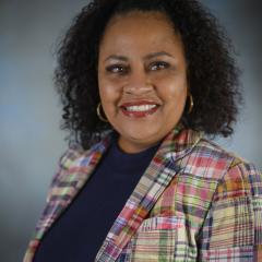 Therasa smiles while posing in front of gray backdrop