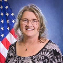 Headshot of LeeAnn Bills in front of the US Flag and a blue background.