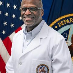 CARE Center employee Mark A. Smith with US and Veterans Affairs flags behind him.
