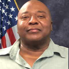 Transition Patient Advocate Reginald Horton smiling in front of American flag.