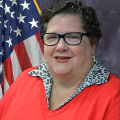 Traci Tam, Alexandria, LA VAMC Patient Patient Advocate smiling in front of American flag. 
