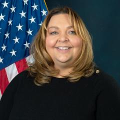 Cindy in front of blue background with US flag.