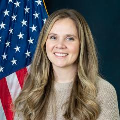 Alison in front of blue background with US flag.
