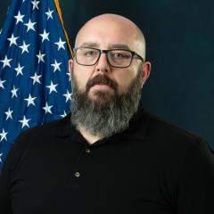 Michael in front of blue background with US flag.