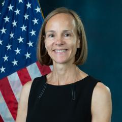 Nicola in front blue background with US flag.