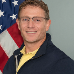 Professional looking man standing in front of U.S. Flag