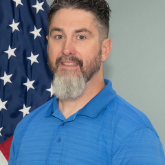 Man standing in front of U.S. flag.