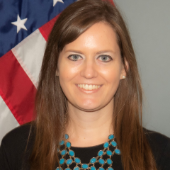 Woman standing in front of U.S. flag.