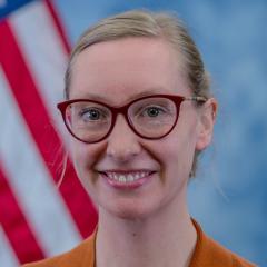 blond woman in front of a flag