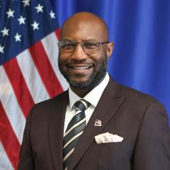 smiling male with the American Flag in the background