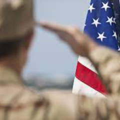 Uniformed service member saluting American flag