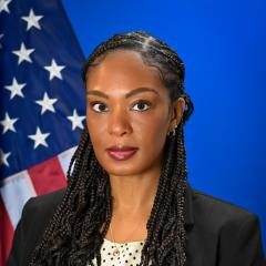 Portrait of a woman with a blue background and an American flag.