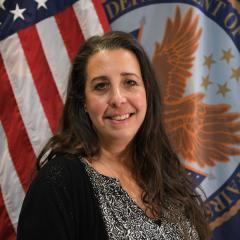 Woman standing in front of an American and Department of Veterans Affairs flags. 