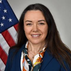 Portrait of a smiling woman in front of an American flag.