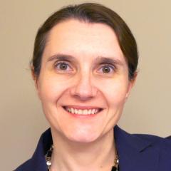 Woman with short brown hair and a blue shirt smiling.