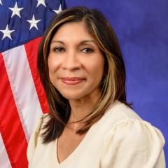 Portrait of woman smiling in front of US flag.