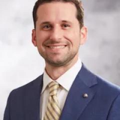 Man in blue suit, striped tie smiling for the camera.