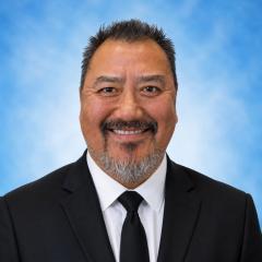 A man with a beard and mustache smiling in a suit and tie.