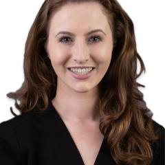 Headshot of a smiling woman with long brown hair and wearing a black top.