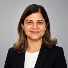 Portrait of a smiling woman in a black blazer and white shirt.