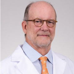 Photograph of a smiling man wearing glasses, a blue shirt, and a white lab coat with an orange tie.