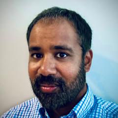 Portrait of a man with a beard wearing a blue and white checkered shirt.