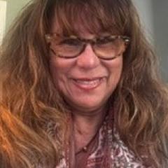 Portrait of a smiling woman with long hair and glasses.