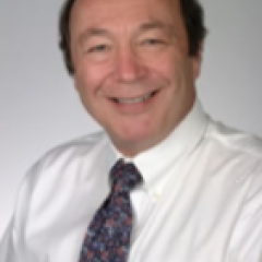 Bald man in a white dress shirt and blue tie smiling.
