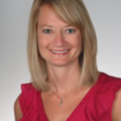 Blonde woman with short hair wearing a red blouse smiling for the camera.