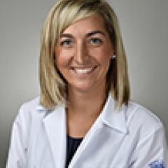 Portrait of smiling woman in white lab coat.