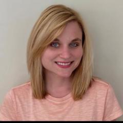 Blonde woman smiling against a plain white background.