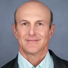 Headshot of a smiling bald man in a striped shirt and jacket.
