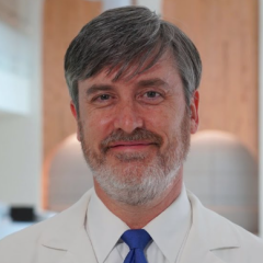 Portrait of a smiling man in a white shirt and blue tie.