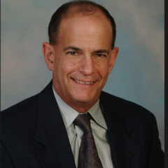 Portrait of a smiling man in a dark suit and tie.