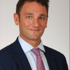Man in navy suit and red tie smiling for the camera.