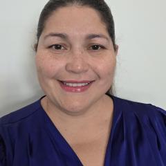 Woman in blue blouse smiling at the camera.