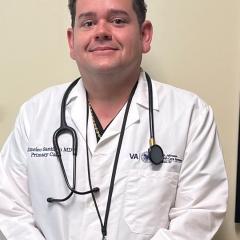 Smiling doctor in white coat with stethoscope around his neck.