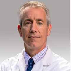 Headshot of a doctor in a white lab coat and blue tie.