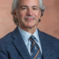 Photograph of a man in a blue suit and striped tie smiling.