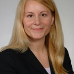 Portrait of a woman with blonde hair smiling, wearing a black blazer.