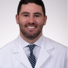 Male doctor in white lab coat and striped tie smiling.