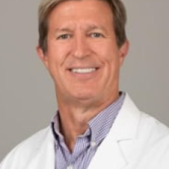 Smiling man in white lab coat with blue name tag, "John, MD".