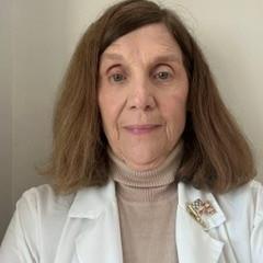 Portrait of an older woman with short brown hair wearing a white lab coat.