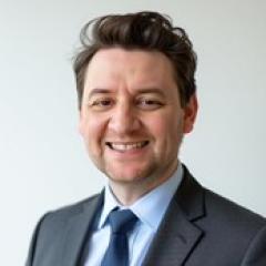 Portrait of a man in a suit and tie smiling.