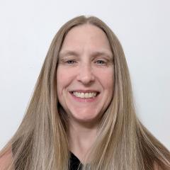 Portrait of a woman with long blonde hair smiling against a white background.