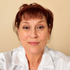 Woman with short brown hair wearing a white lab coat.