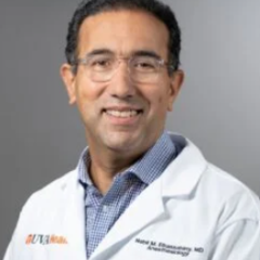 Smiling man in white lab coat and glasses poses for photo.